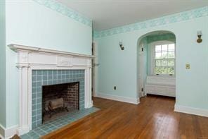 unfurnished living room with a tile fireplace and dark hardwood / wood-style flooring