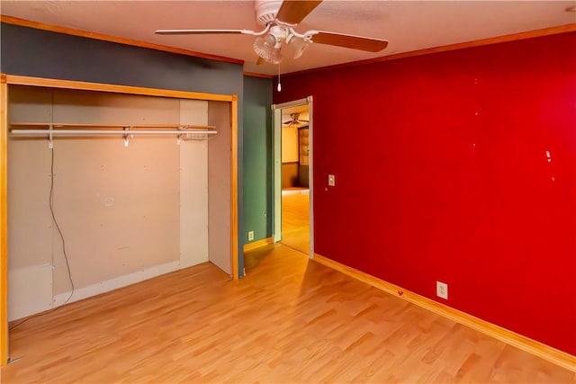 unfurnished bedroom with ceiling fan, wood-type flooring, crown molding, and a closet