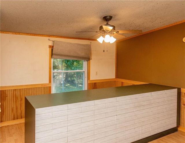 kitchen featuring wood walls, ceiling fan, a textured ceiling, and hardwood / wood-style flooring