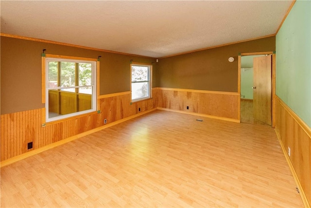 unfurnished room featuring a textured ceiling, hardwood / wood-style flooring, crown molding, and wood walls