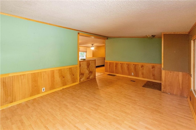 spare room with hardwood / wood-style floors, ceiling fan, a textured ceiling, and wooden walls