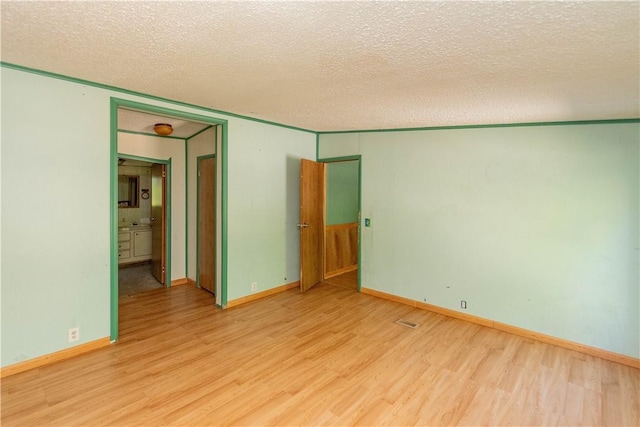 spare room with a textured ceiling and light hardwood / wood-style floors