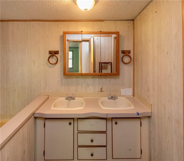 bathroom with a textured ceiling, vanity, and wooden walls