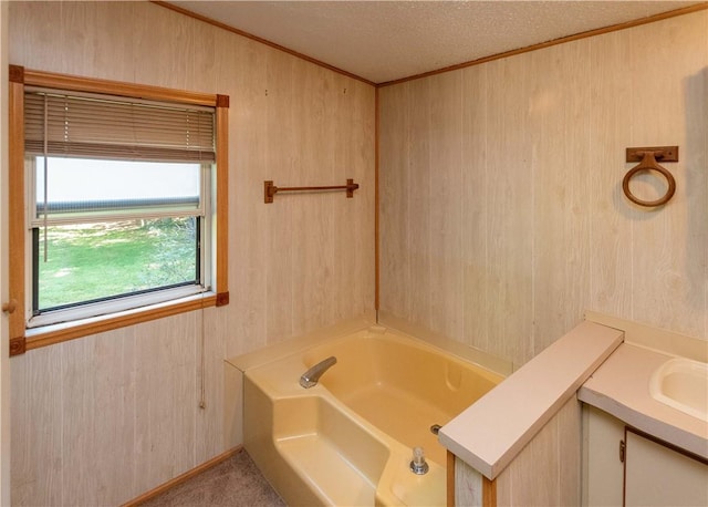 bathroom featuring wooden walls, vanity, a bath, and a textured ceiling