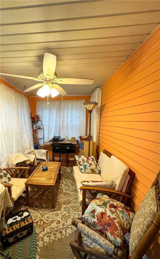 living room featuring ceiling fan and wood walls