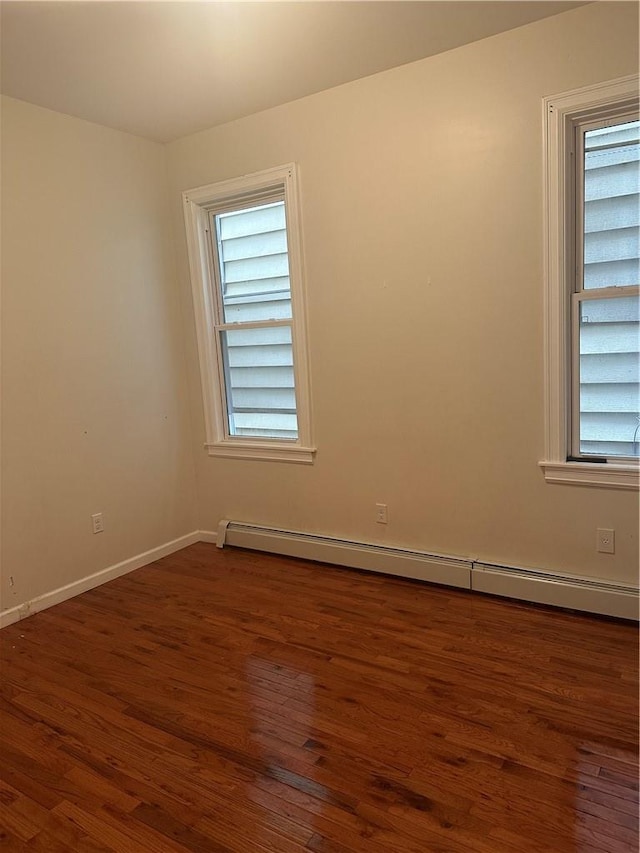 empty room with baseboard heating and dark hardwood / wood-style floors