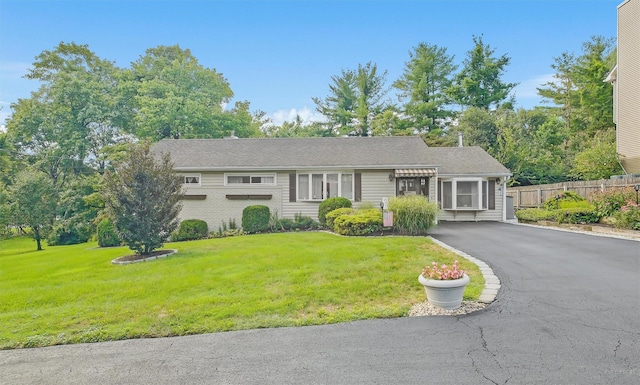 single story home featuring driveway, fence, and a front yard