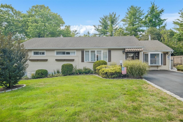 view of front of property with roof with shingles, aphalt driveway, and a front lawn