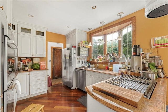 kitchen with dark hardwood / wood-style flooring, white cabinets, pendant lighting, and appliances with stainless steel finishes