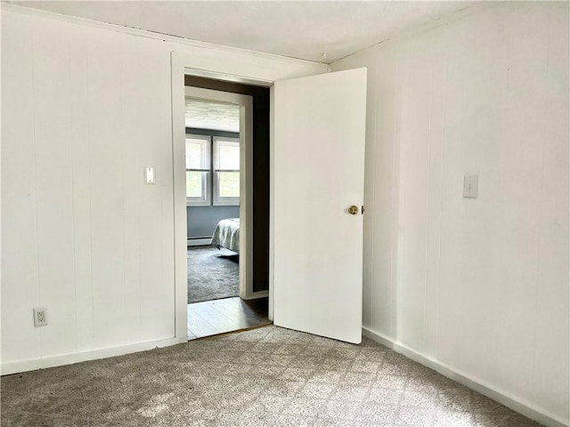 carpeted spare room with a baseboard heating unit