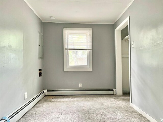 carpeted empty room with ornamental molding, electric panel, and a baseboard heating unit