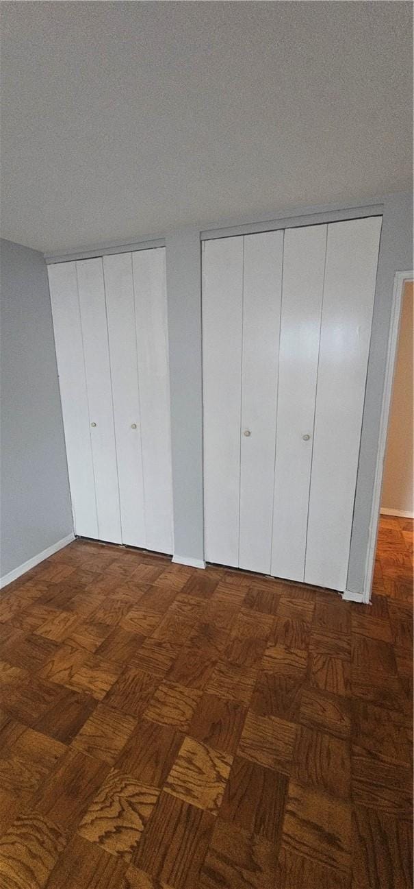 unfurnished bedroom featuring dark parquet floors and a textured ceiling