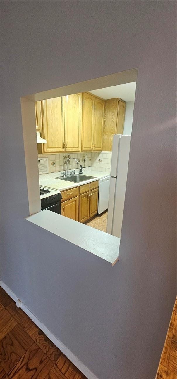 kitchen with decorative backsplash, light brown cabinets, white appliances, and sink