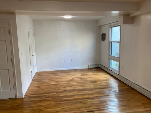 spare room featuring plenty of natural light, a baseboard heating unit, and light hardwood / wood-style flooring