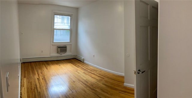 unfurnished room with baseboard heating, an AC wall unit, and hardwood / wood-style flooring