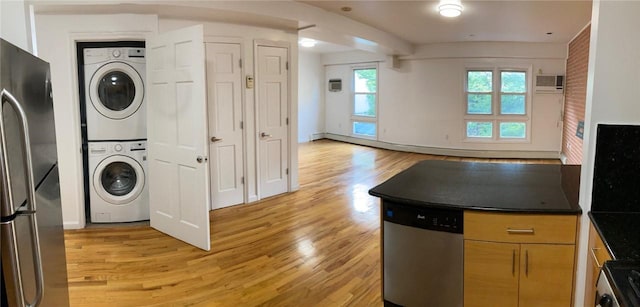 kitchen featuring appliances with stainless steel finishes, light brown cabinets, stacked washing maching and dryer, and light hardwood / wood-style floors