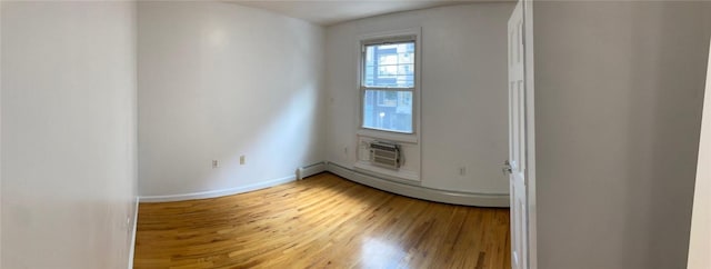 unfurnished room with hardwood / wood-style flooring, a wall mounted air conditioner, and a baseboard radiator