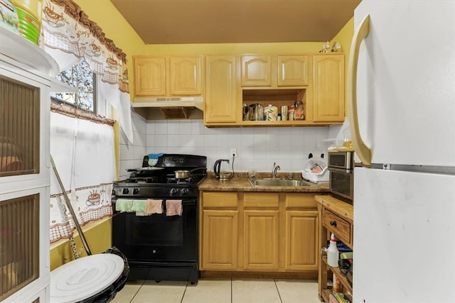 kitchen with backsplash, white refrigerator, sink, light tile patterned floors, and black range with gas cooktop