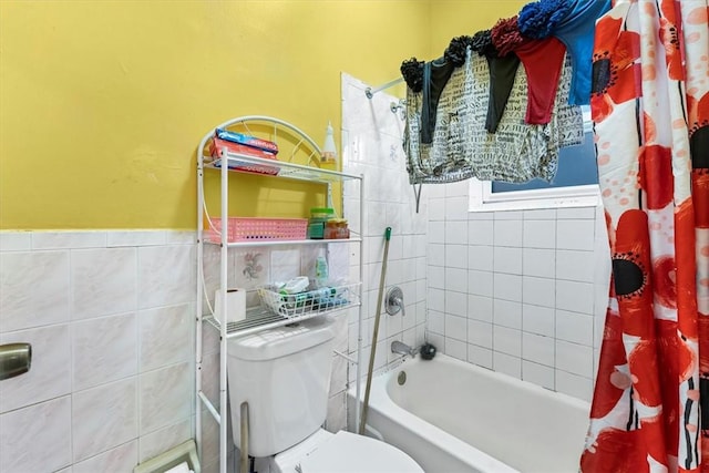 bathroom featuring toilet, shower / bath combo with shower curtain, and tile walls