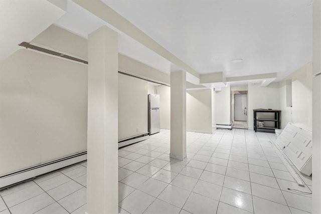 basement with white fridge, light tile patterned floors, and a baseboard heating unit