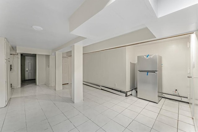 basement featuring light tile patterned floors, a baseboard radiator, and fridge