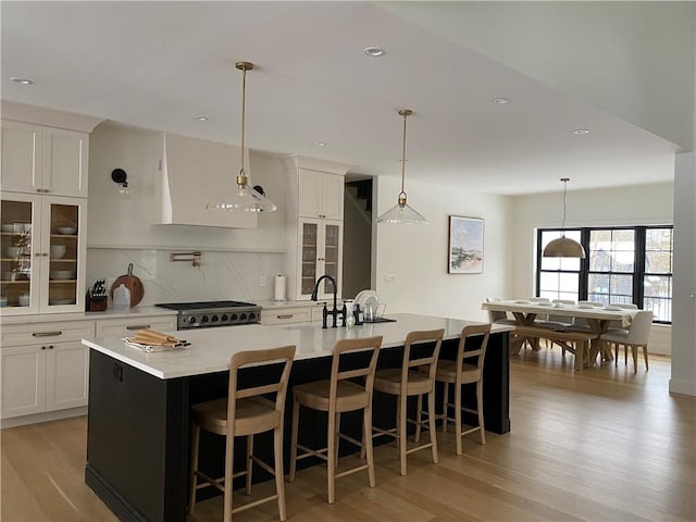 kitchen featuring a kitchen breakfast bar, stainless steel range oven, a spacious island, light hardwood / wood-style floors, and white cabinets