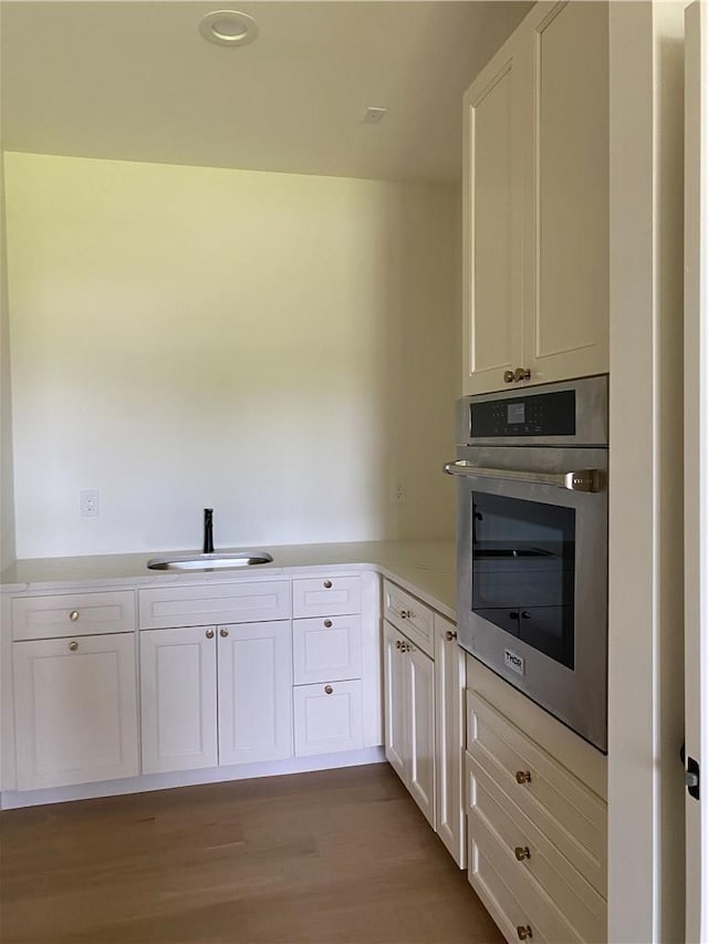 kitchen with white cabinets, sink, light hardwood / wood-style flooring, and stainless steel oven