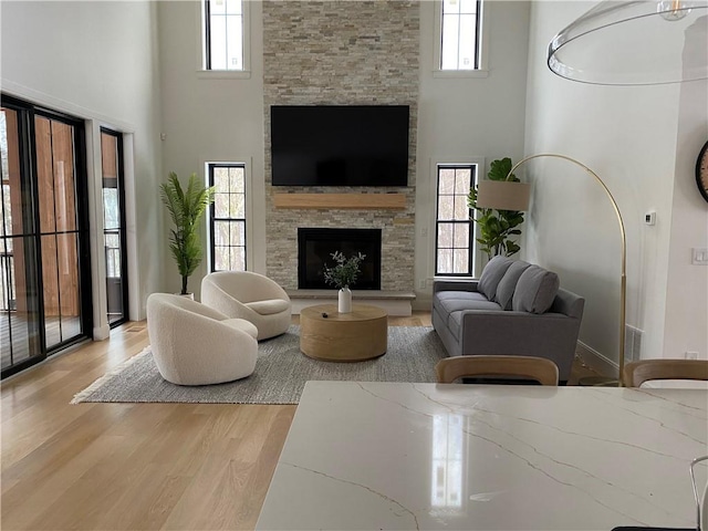 living room with light hardwood / wood-style flooring, a healthy amount of sunlight, and a high ceiling