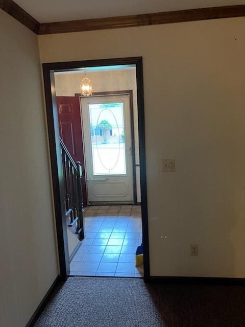 entryway with a notable chandelier, light tile patterned flooring, and ornamental molding