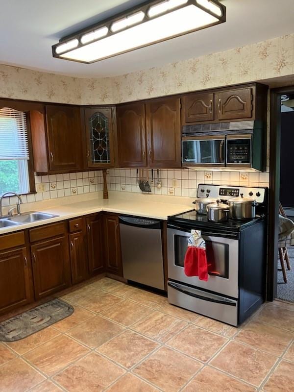 kitchen featuring decorative backsplash, sink, dark brown cabinets, and appliances with stainless steel finishes