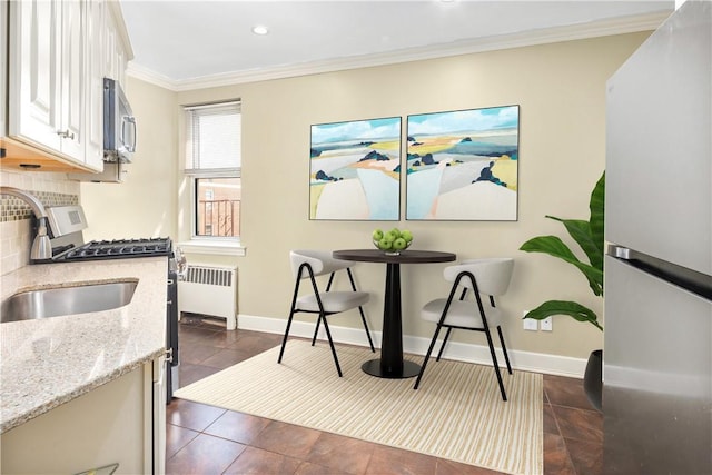 kitchen featuring radiator heating unit, crown molding, tasteful backsplash, light stone counters, and white cabinetry