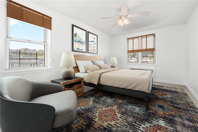 bedroom featuring multiple windows, radiator heating unit, carpet floors, and ceiling fan