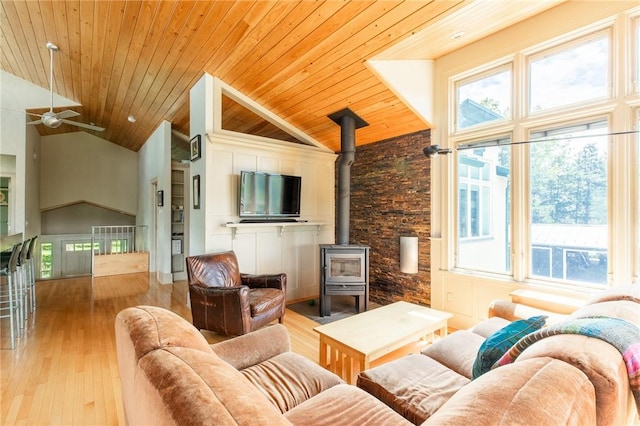 living room with wood ceiling, a wood stove, light hardwood / wood-style flooring, and a healthy amount of sunlight