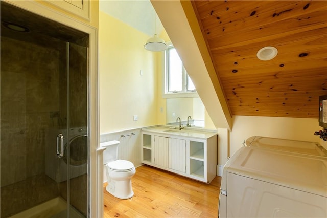 bathroom featuring wooden ceiling, hardwood / wood-style floors, a shower with door, toilet, and washer and clothes dryer