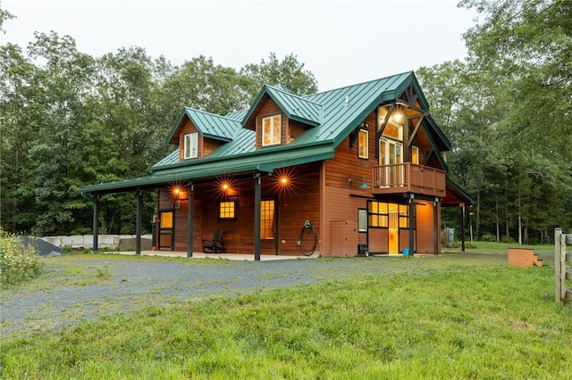 rear view of house with a balcony and a yard