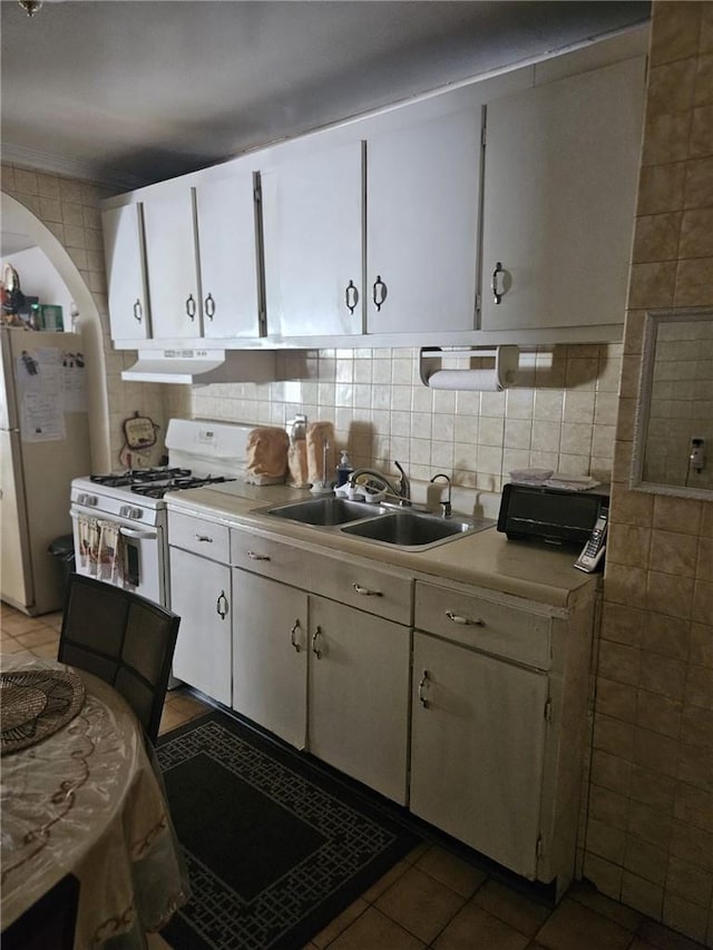 kitchen featuring tile patterned floors, fridge, decorative backsplash, white cabinets, and white gas range oven