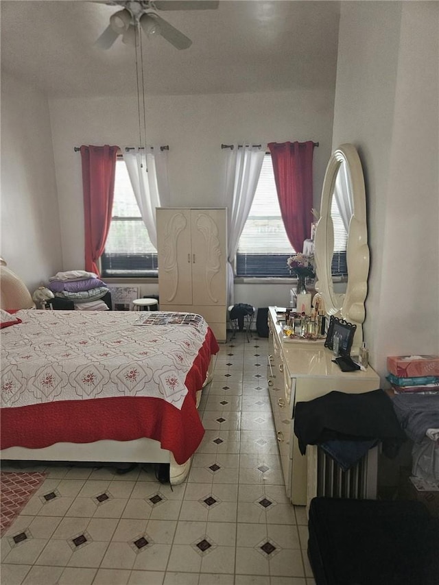 tiled bedroom featuring multiple windows and ceiling fan