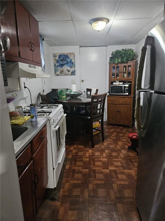 kitchen featuring a paneled ceiling, dark parquet flooring, and stainless steel appliances