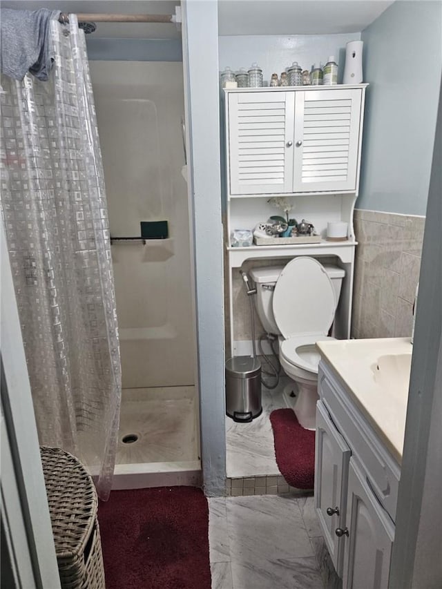 bathroom with toilet, vanity, tile walls, and walk in shower