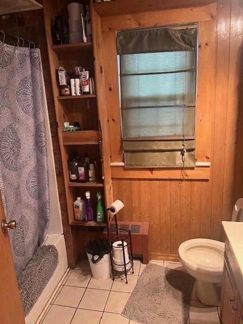 full bathroom featuring shower / bath combo, tile patterned floors, vanity, toilet, and wood walls