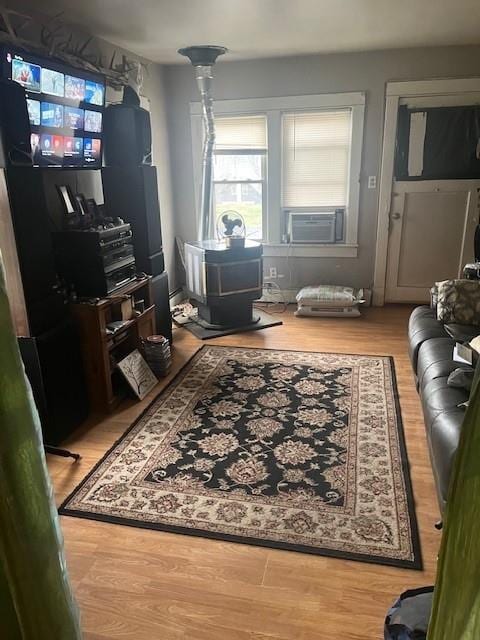 living room featuring hardwood / wood-style flooring, a wood stove, and cooling unit