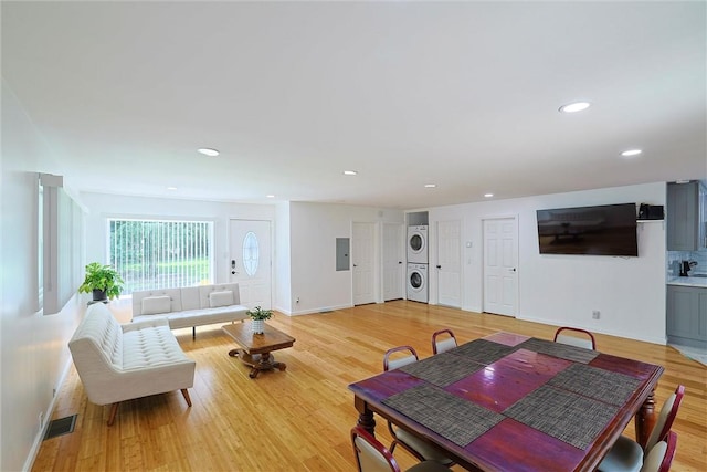 interior space featuring light wood-type flooring, stacked washer / dryer, and electric panel