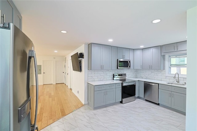 kitchen with light wood-type flooring, stainless steel appliances, gray cabinets, and sink