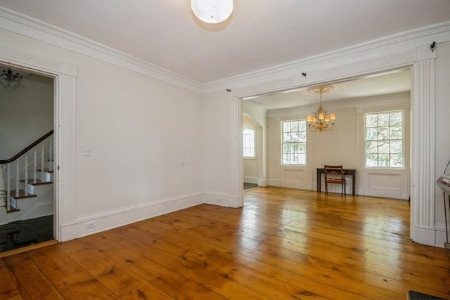 unfurnished room featuring hardwood / wood-style flooring, crown molding, and a notable chandelier