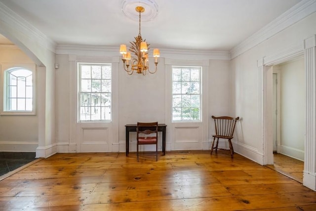 interior space with hardwood / wood-style floors, ornamental molding, a wealth of natural light, and an inviting chandelier