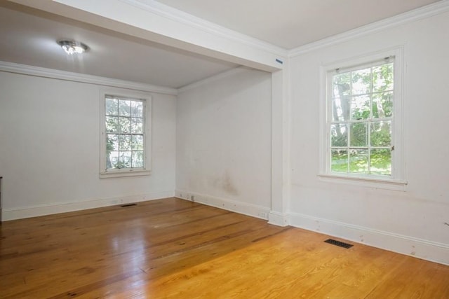 spare room with wood-type flooring, crown molding, and a healthy amount of sunlight