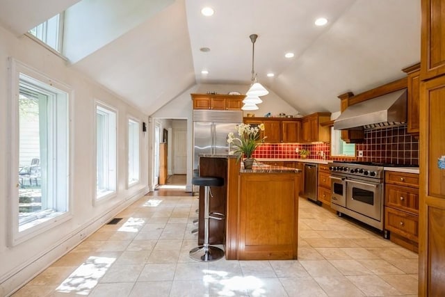 kitchen with a kitchen island, high end appliances, plenty of natural light, and wall chimney range hood