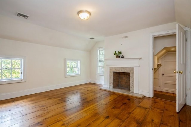 unfurnished living room featuring a healthy amount of sunlight, lofted ceiling, and wood-type flooring