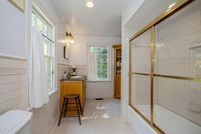 full bathroom featuring tile patterned flooring, bath / shower combo with glass door, tile walls, and a wealth of natural light