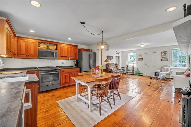 kitchen featuring pendant lighting, stainless steel appliances, a baseboard radiator, and light wood-type flooring